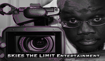 Image of a video camera outlined in purple sitting on a table next to Anthony Amos' face leaning in next to it. He is a dark skinned bald man wearing glasses and looking straight forward.